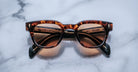Jacques Marie Mage Julien in Argyle  rectangular sunglass in warm tortoiseshell acetate with amber and dark brown marbling, featuring a keyhole bridge, signature arrowhead front pins, and exposed metal core detailing within the temples, shown with lightly tinted lenses.