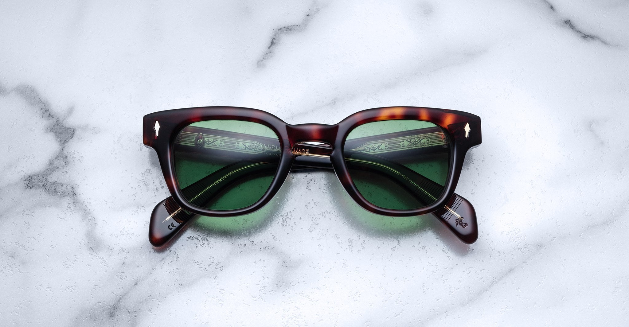 Jacques Marie Mage Julien in Havana 5 rectangular sunglass in brown tortoiseshell acetate with warm amber undertones, featuring a keyhole bridge, signature arrowhead front pins, and exposed metal core detailing within the temples, fitted with green-tinted lenses.