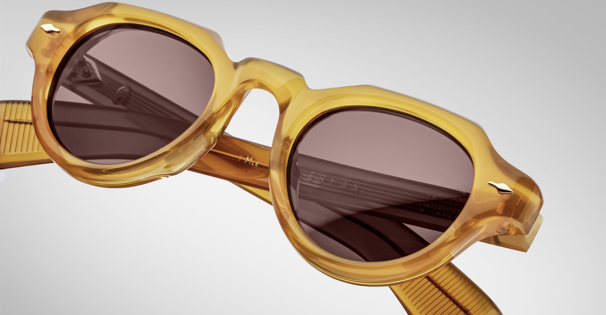 Close-up of Jacques Marie Mage Kellerman sunglasses featuring thick, translucent yellow frames and dark round lenses. The light, blurred background accentuates the eyewear’s texture and stylish details.
