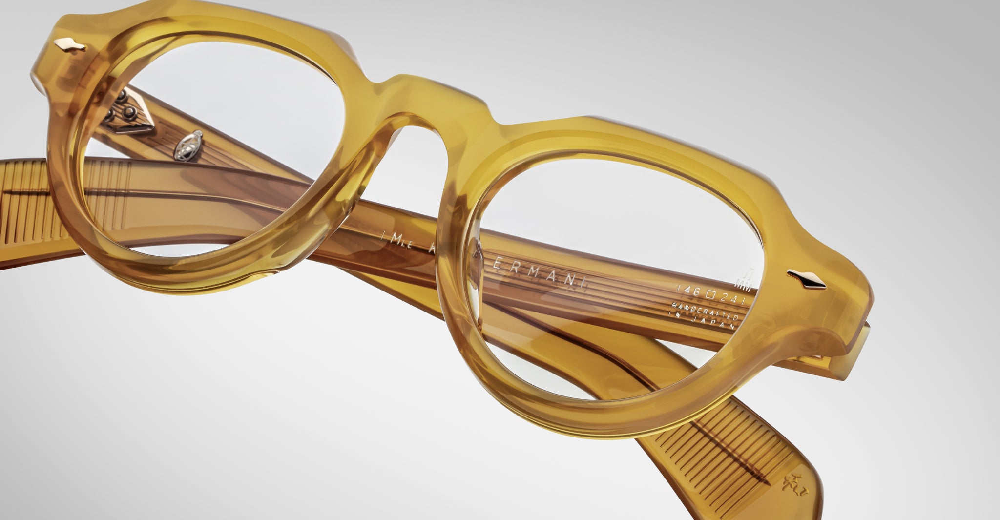 Close-up of Jacques Marie Mage Kellerman eyeglasses—round, translucent yellow frames with thick rims and folded arms—set against a light gray background.