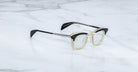 Jacques Marie Mage Kennedy eyeglasses with clear frames and black arms, shown from above.
