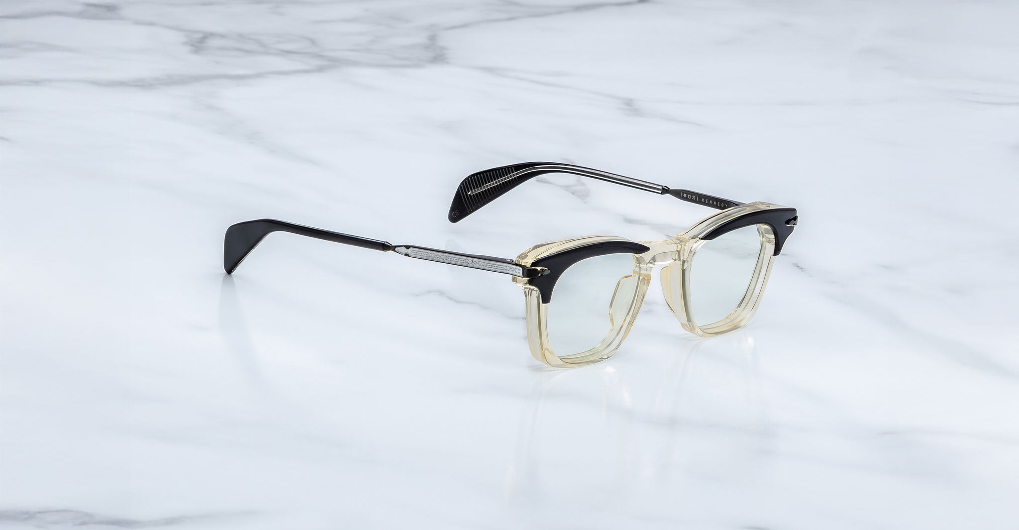 Jacques Marie Mage Kennedy eyeglasses with clear frames and black arms, shown from above.