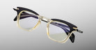 Jacques Marie Mage Kennedy eyeglasses, rectangular shape, clear and black translucent frames with reflective lenses, front view.