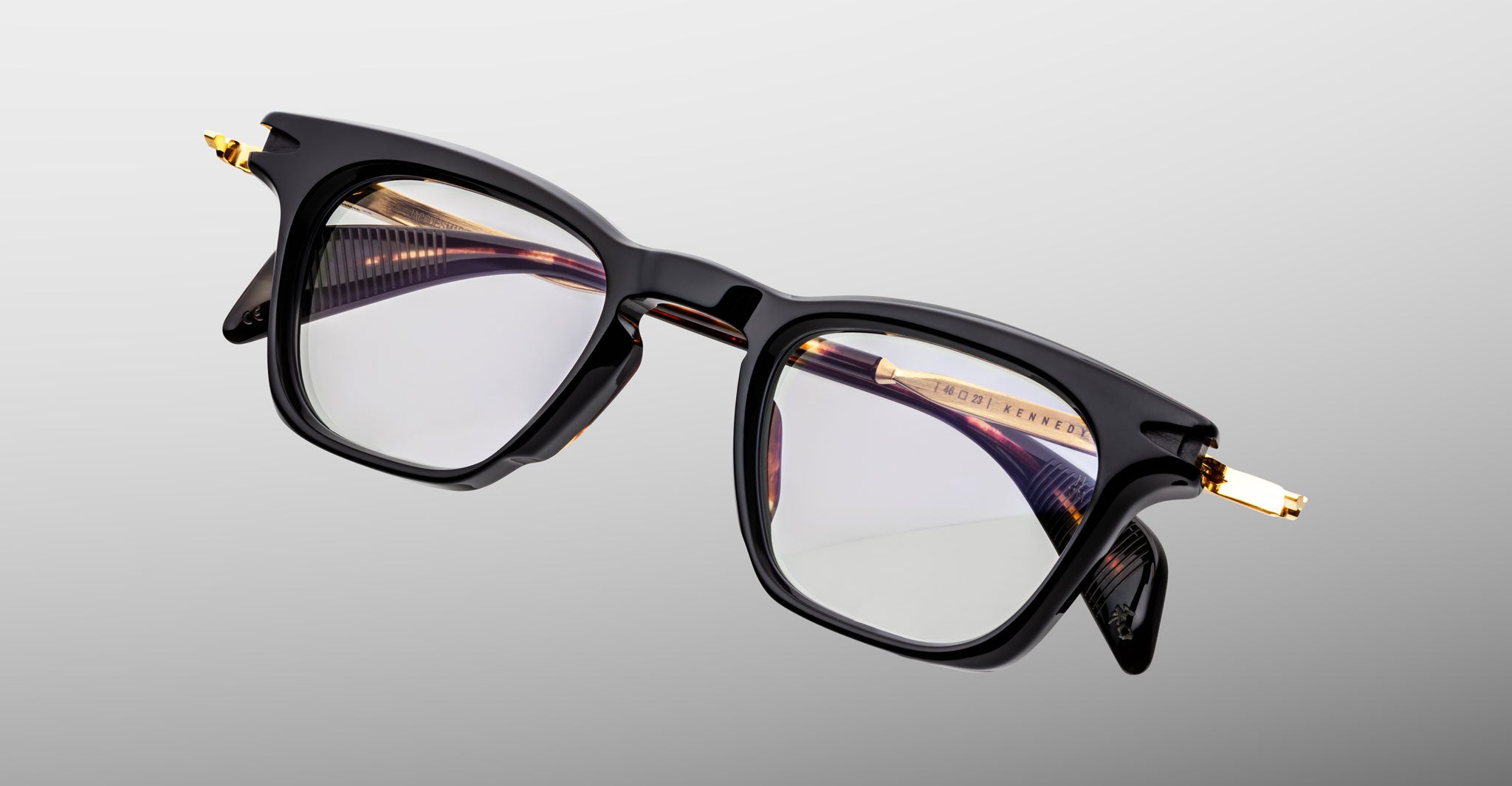 Jacques Marie Mage Kennedy black rectangular eyeglasses with gold temple accents, front angle view.