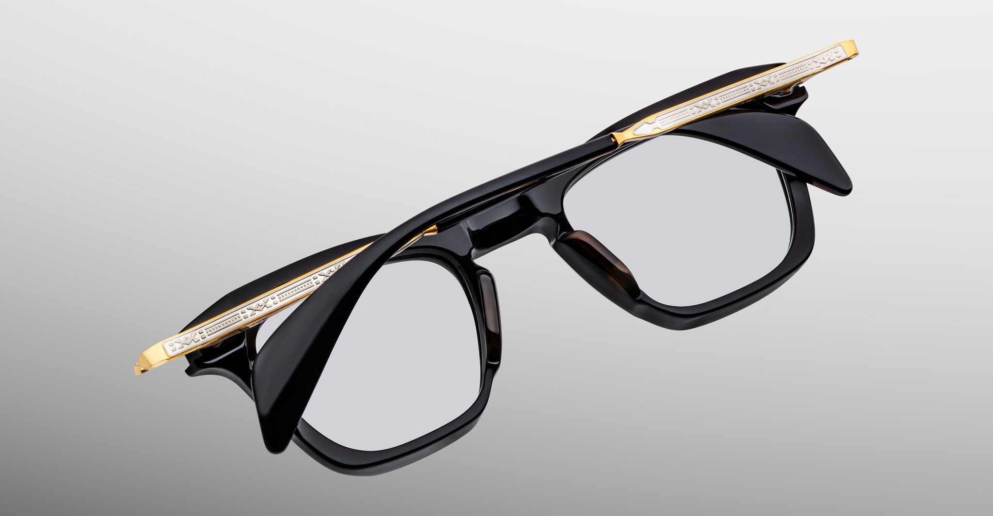 Jacques Marie Mage Kennedy eyeglasses with bold black and gold frames, engraved temples, front angle view.