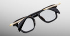 Jacques Marie Mage Kennedy eyeglasses with bold black and gold frames, engraved temples, front angle view.
