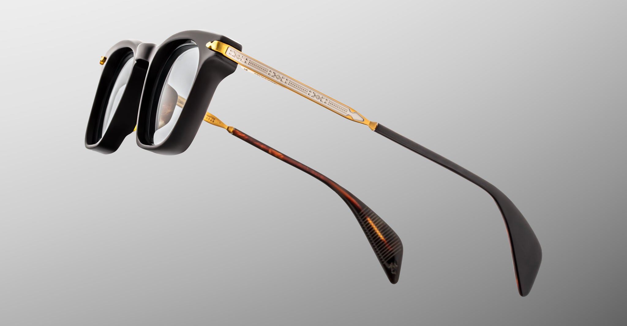Jacques Marie Mage Kennedy eyeglasses, black thick frames, gold accents on arms, tortoiseshell tips, front angle view.