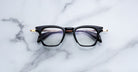 Jacques Marie Mage Kennedy eyeglasses with black rims and gold accents, front view.