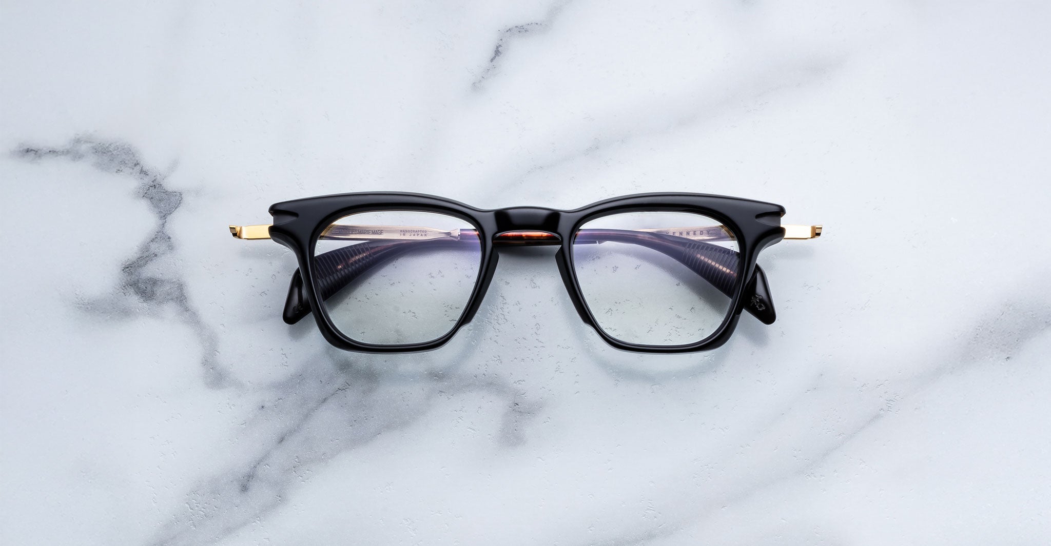 Jacques Marie Mage Kennedy eyeglasses with black rims and gold accents, front view.