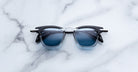 Jacques Marie Mage Kennedy sunglasses, black and silver frame with blue lenses, front view.
