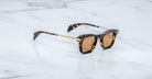Jacques Marie Mage Kennedy sunglasses with brown lenses and gold accents, viewed from above.
