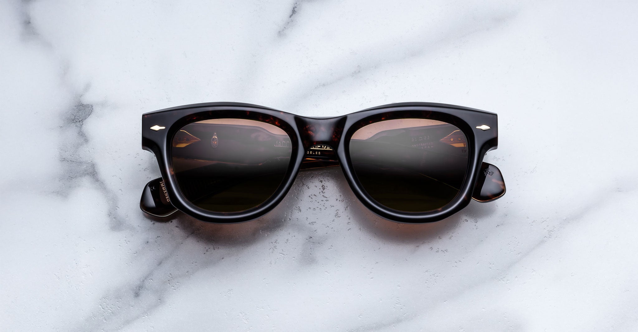 Jacques Marie Mage Kinshasa sunglasses with dark lenses, top view, reflecting a car dashboard.