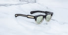 Jacques Marie Mage Kinshasa sunglasses, black and gold frame with green lenses, shown from above.