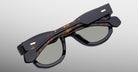 Jacques Marie Mage Kinshasa sunglasses, black frames with tortoiseshell arms, top-down view.