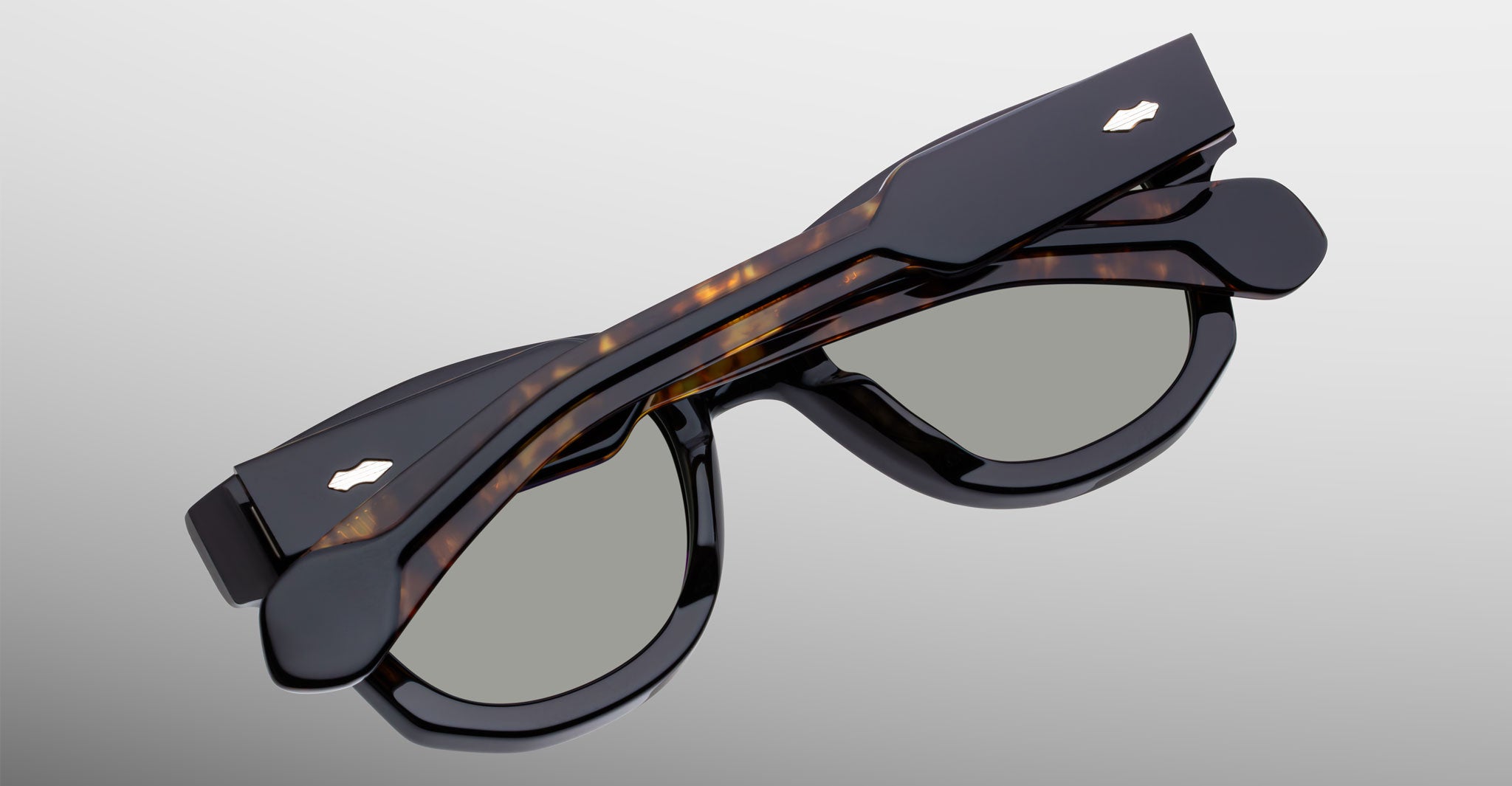 Jacques Marie Mage Kinshasa sunglasses, black frames with tortoiseshell arms, top-down view.