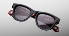 Jacques Marie Mage Kinshasa sunglasses, black polarized frames, dark lenses, red arms, front view.