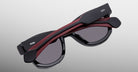 Jacques Marie Mage Kinshasa sunglasses, folded, black frame, dark lenses, red accent, silver logo on the arms, side view.
