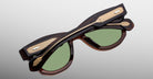 Jacques Marie Mage Kinshasa sunglasses, folded, shown from above with green lenses, brown frames, and gold arm accents.