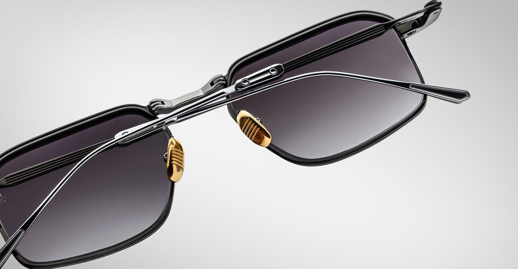 The Jacques Marie Mage Koenig sunglasses feature black rectangular lenses, metal frames, dark tints, adjustable nose pads, and thin textured arms. Displayed against a light gray background.