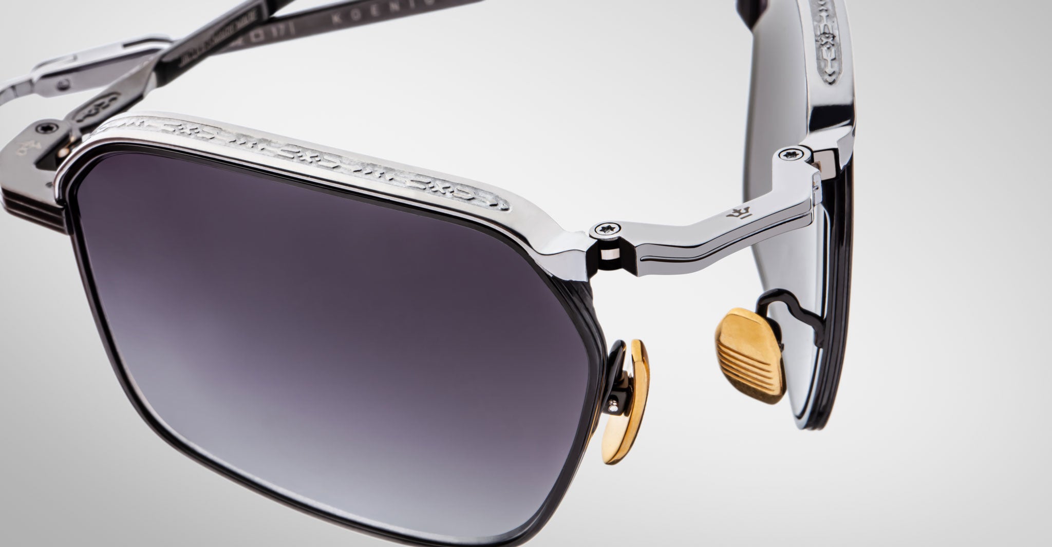 Close-up of Jacques Marie Mage Koenig sunglasses showcasing a metal frame, tinted square lenses, gold nose pads, and intricate hinge and temple detailing.