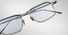 Close-up view of Jacques Marie Mage Koenig eyeglasses, featuring silver metal frames with rectangular lenses and gold nose pads, shown at an angle to highlight frame details and temples against a light background.