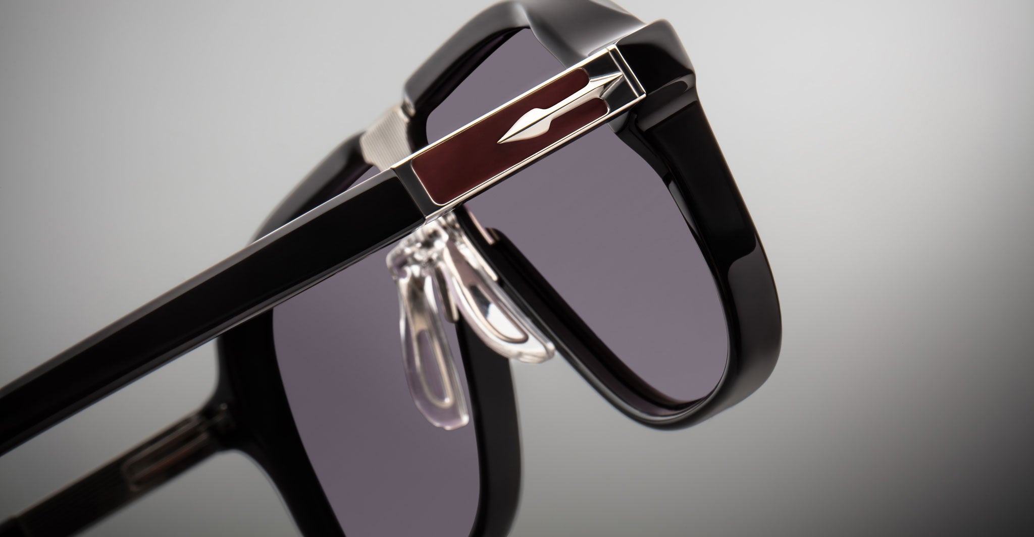 Close-up view of Jacques Marie Mage Kurokawa sunglasses in black with dark lenses and silver accents, showcasing the hinge and nose pads against a neutral background.