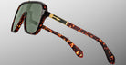 The Jacques Marie Mage Kurokawa sunglasses feature large green-tinted lenses, tortoiseshell frames with gold accents on the arms, and a modern design, shown against a plain gray background.