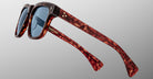 The Jacques Marie Mage Lankaster sunglasses feature a tortoiseshell pattern, blue lenses, thick frames, and gold accents on the arms, shown from a side angle against a plain light gray background.