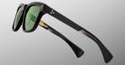 The Jacques Marie Mage Lankaster sunglasses feature black frames with green lenses, gold star-shaped accents, and thick angular arms, displayed against a plain light gray background.