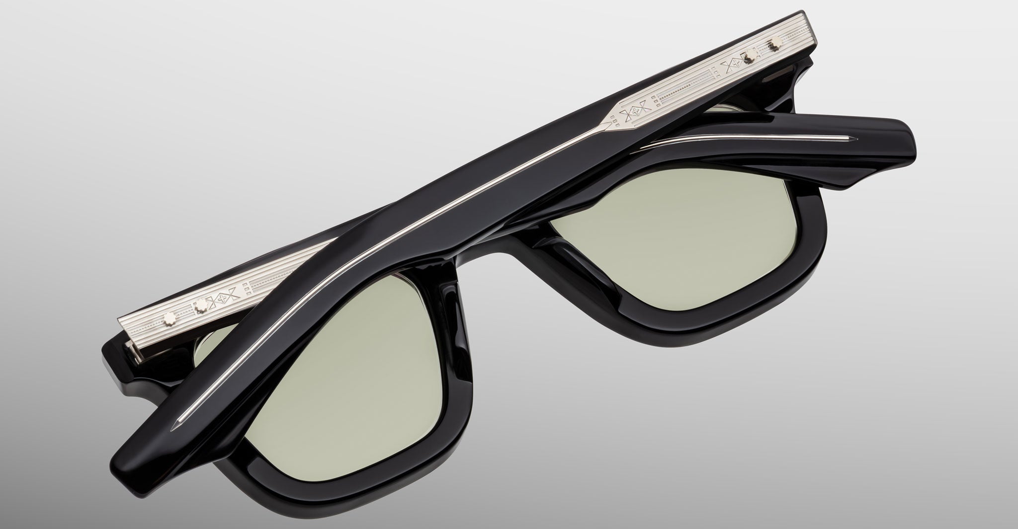 The Jacques Marie Mage Leclair sunglasses, featuring a black rectangular frame with light lenses and silver metal accents engraved on the arms, are shown folded against a neutral background.