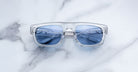 Jacques Marie Mage Louisville sunglasses with clear frames and blue lenses, metallic accents visible, shown from a front angle.