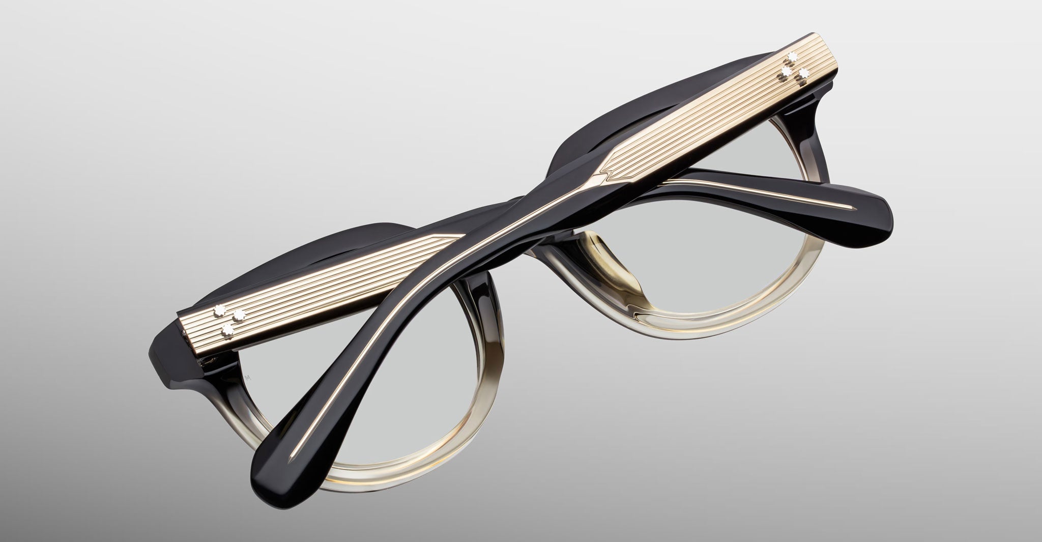 Jacques Marie Mage Matsu eyeglasses with thick black and gold frames and clear lenses, viewed from above.