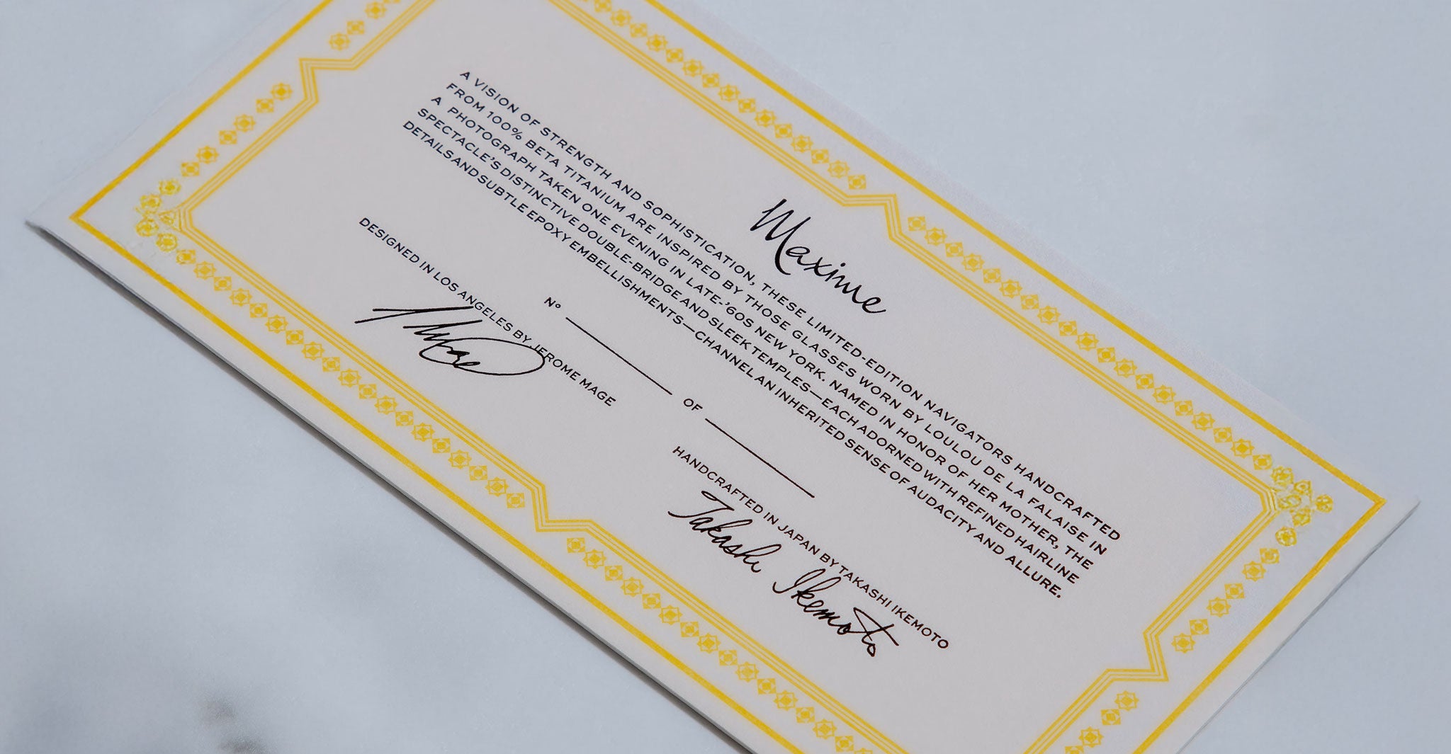 Close-up of Jacques Marie Mage Maxime eyeglasses certificate with yellow border and signatures, viewed from above.