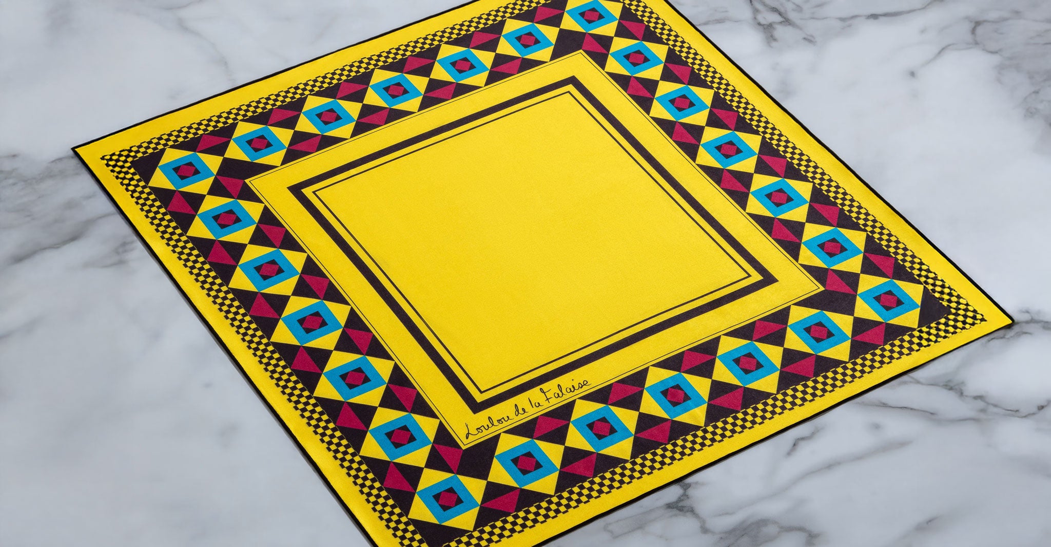 Jacques Marie Mage Maxime yellow square scarf with red, blue, and black geometric border, top view.