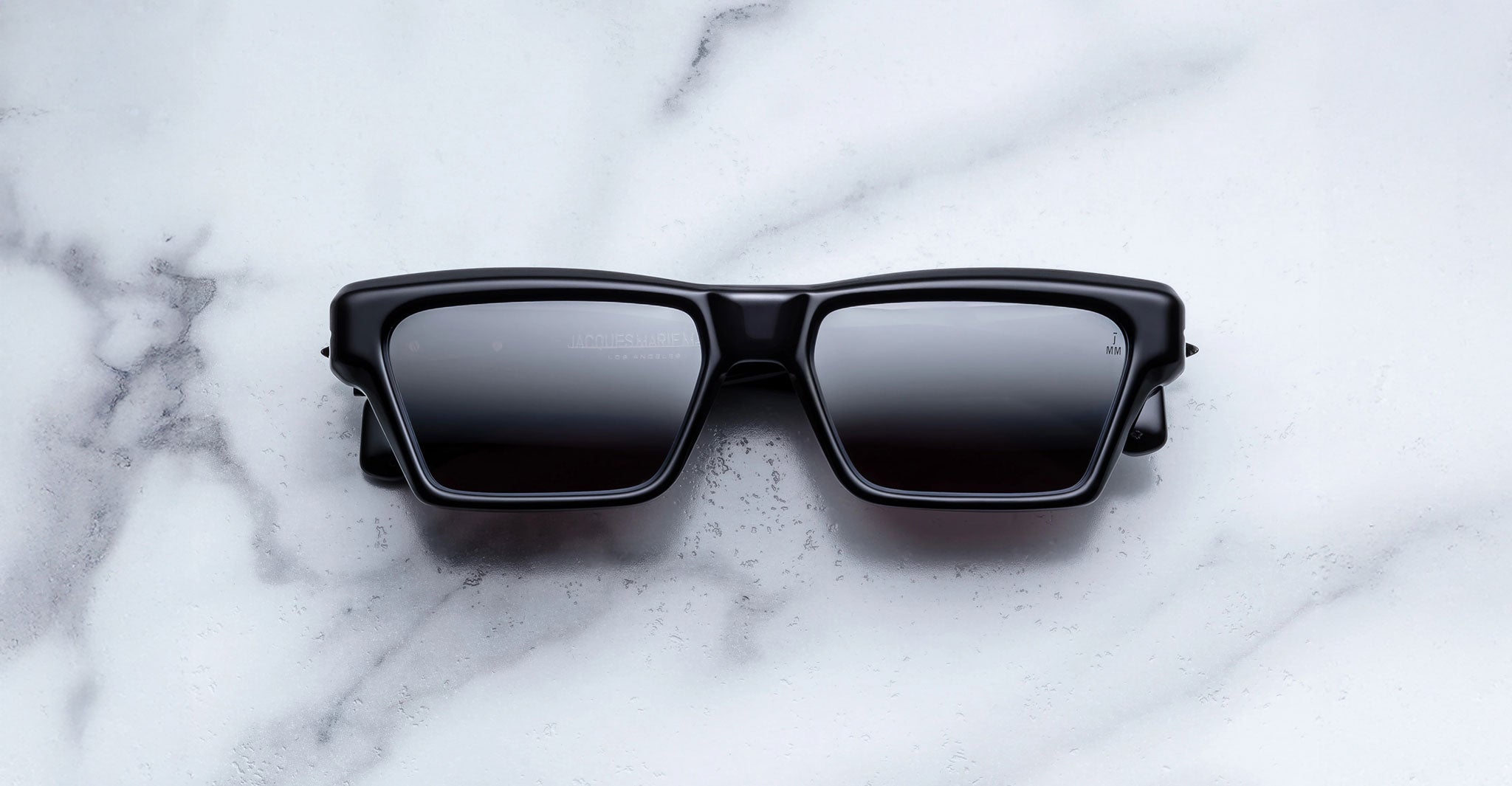 Jacques Marie Mage Melchior black rectangular sunglasses with dark lenses, top view.