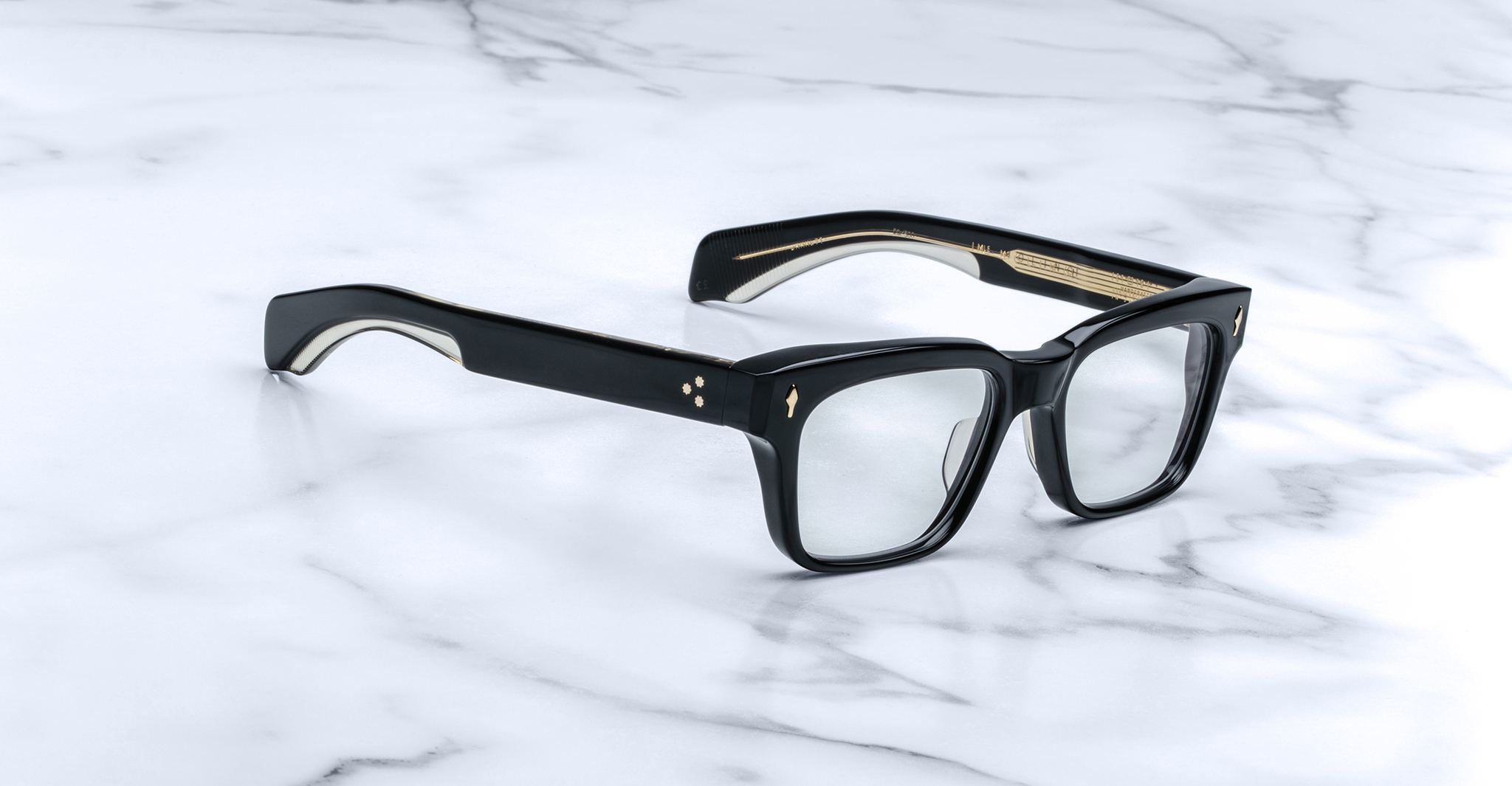 Jacques Marie Mage Molino black eyeglasses with clear lenses and gold accents, shown from above.