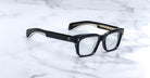 Jacques Marie Mage Molino black eyeglasses with clear lenses and gold accents, shown from above.