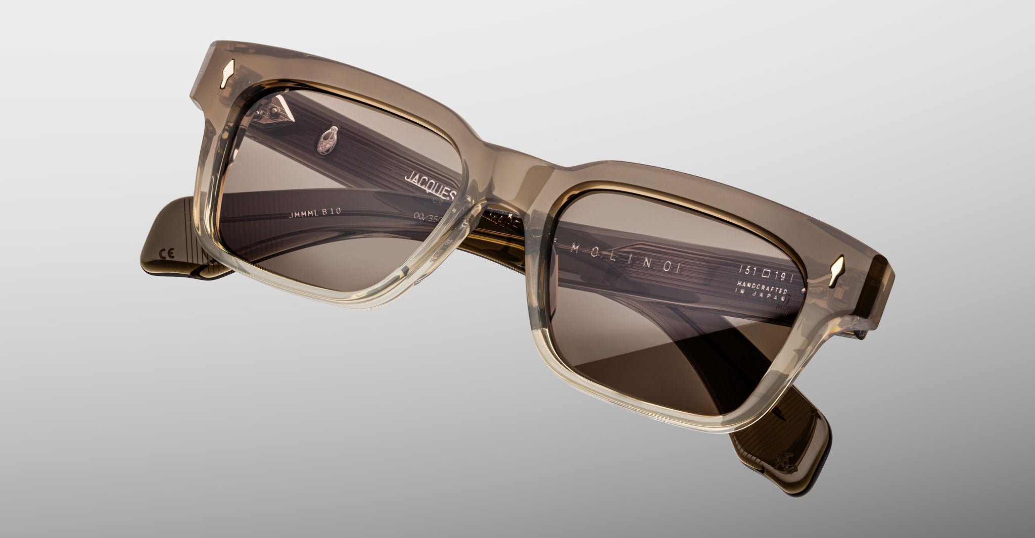 The Jacques Marie Mage Molino by COMING SOON features rectangular sunglasses with thick, translucent brown frames and dark lenses, displayed on a light gray background.