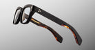The Jacques Marie Mage Molino by COMING SOON: black rectangular eyeglasses with thick frames and tortoiseshell-patterned inner arms, displayed on a light gray background.