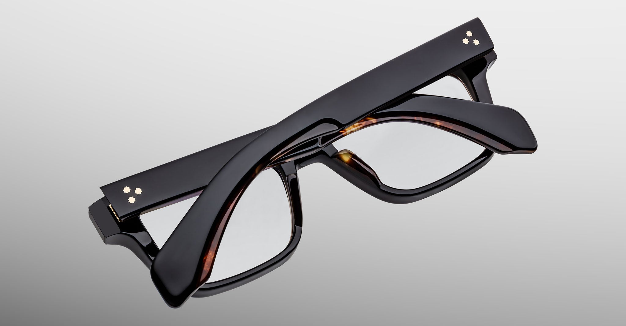 A pair of Jacques Marie Mage Molino black eyeglasses by COMING SOON, folded flat with arms crossed, displayed on a plain light gray background.