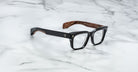 Jacques Marie Mage Molino black rectangular eyeglasses with wood-patterned temples, shown from above.