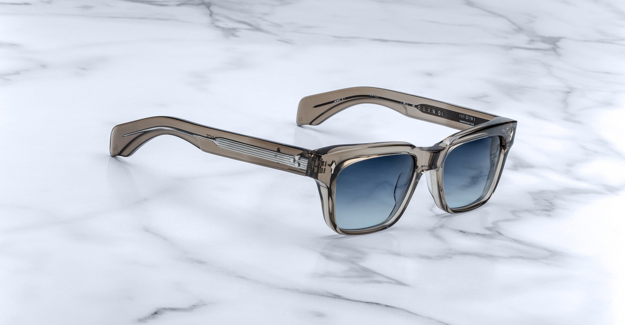 Jacques Marie Mage Molino sunglasses with translucent brown frames and blue gradient lenses, shown from above.