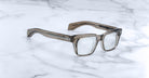 Jacques Marie Mage Molino thick translucent brown rectangular eyeglasses, top view, displayed on surface.