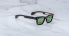 Jacques Marie Mage Molino black rectangular sunglasses with green lenses and gold accents, top view.
