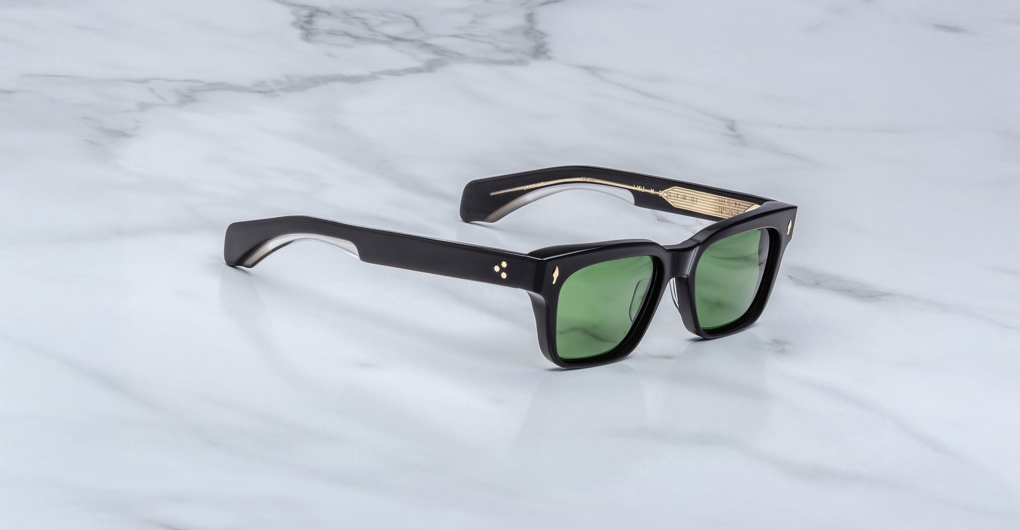 Jacques Marie Mage Molino black rectangular sunglasses with green lenses and gold accents, top view.