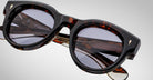 Close-up of Jacques Marie Mage Molitor sunglasses featuring stylish tortoiseshell frames, dark round lenses, and gold-accented arms, set against a light gray background.