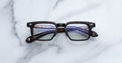 Jacques Marie Mage Moscova in Beau acetate optical frame, front-facing view with rectangular lenses, rich tortoiseshell acetate, signature arrowhead pins, and visible core wire temples with warm tonal detailing