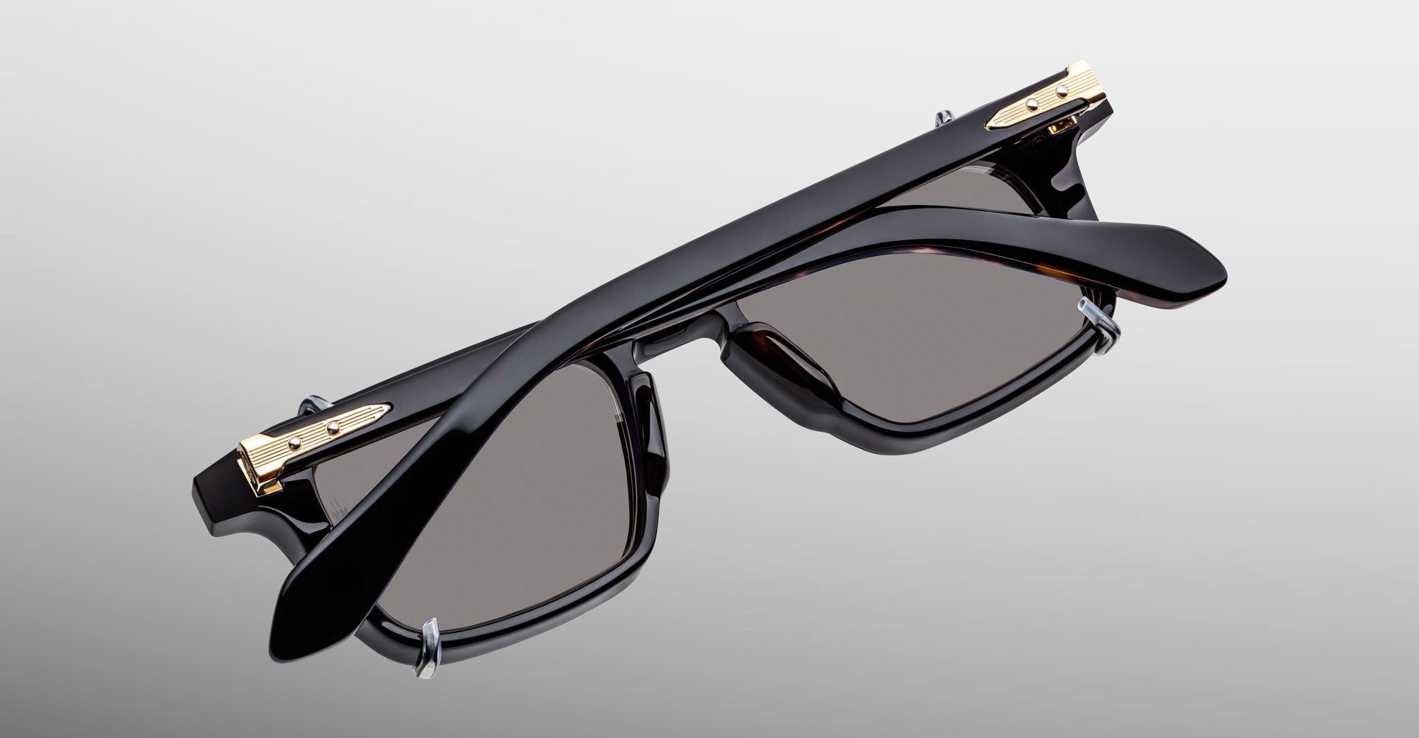Jacques Marie Mage Moscova in Noir 15 acetate optical frame with Black clip-on, top-down angled view showcasing rectangular silhouette, polished black acetate, arrowhead front pins, gold monoblock hinges, and dark-tinted clip-on lenses