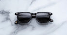 Jacques Marie Mage Moscova in Noir 15 acetate optical frame with Black clip-on, front-facing view featuring rectangular dark-tinted lenses, polished black acetate, signature arrowhead pins, and slim black clip-on attachment across the bridge