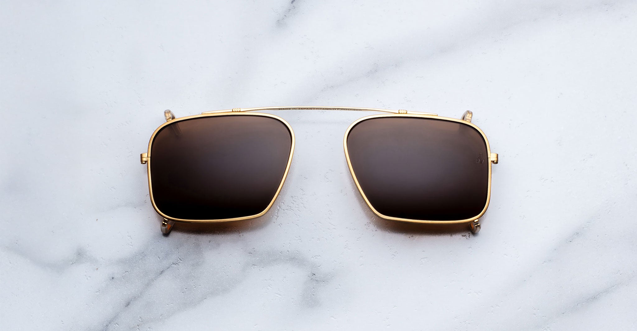 Jacques Marie Mage Moscova clip-on in Gold, front-facing view with rectangular brown-tinted lenses, slim gold metal frame, and bridge-mounted clip mechanism designed to attach seamlessly to Moscova optical frames